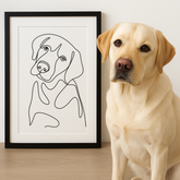 Dog sitting next to a framed line drawing of a dog on a wooden surface.